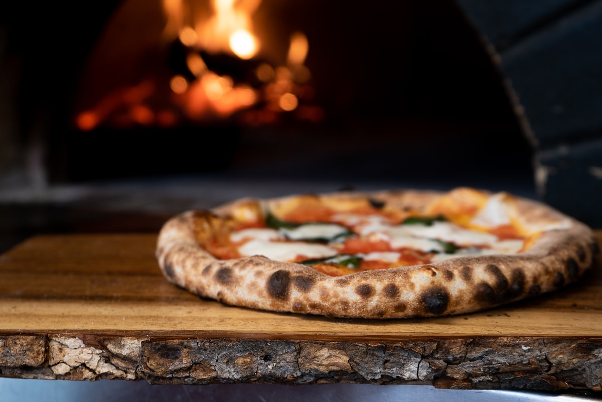 Pizza baking inside a glowing brick wood-fired oven